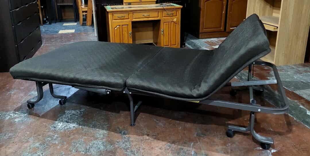 Reclining Folding Bed (Category: Bed Frames & Mattresses) located in Manila. Submitted by luckyfalcon.510cbb (Listing ID 1428741692, Image 3). Description: Folding bed features a dark-colored, padded surface and a sturdy metal frame. It has wheels for easy movement and can be folded for storage. The bed can be adjusted to different positions, including a flat and a reclined position. Dimensions are approximately H-12, L-76, and W-36 inches..