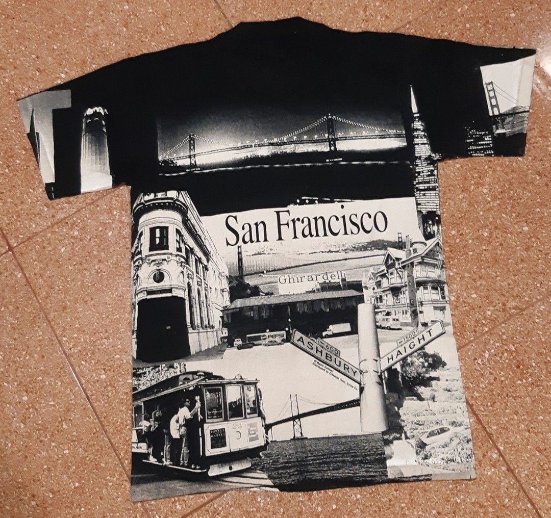 All Sport San Francisco Graphic Tee (Category: Tshirts & Polo Shirts ) located in Malaybalay. Submitted by rielstuff (Listing ID 1428952947, Image 2). Description: Black t-shirt featuring a San Francisco graphic print. The print includes images of the Golden Gate Bridge, cable cars, and other landmarks. The tag indicates it is an All Sport Maxweight, preshrunk, made in the USA, and is a size M (40). It is made of 100% cotton..