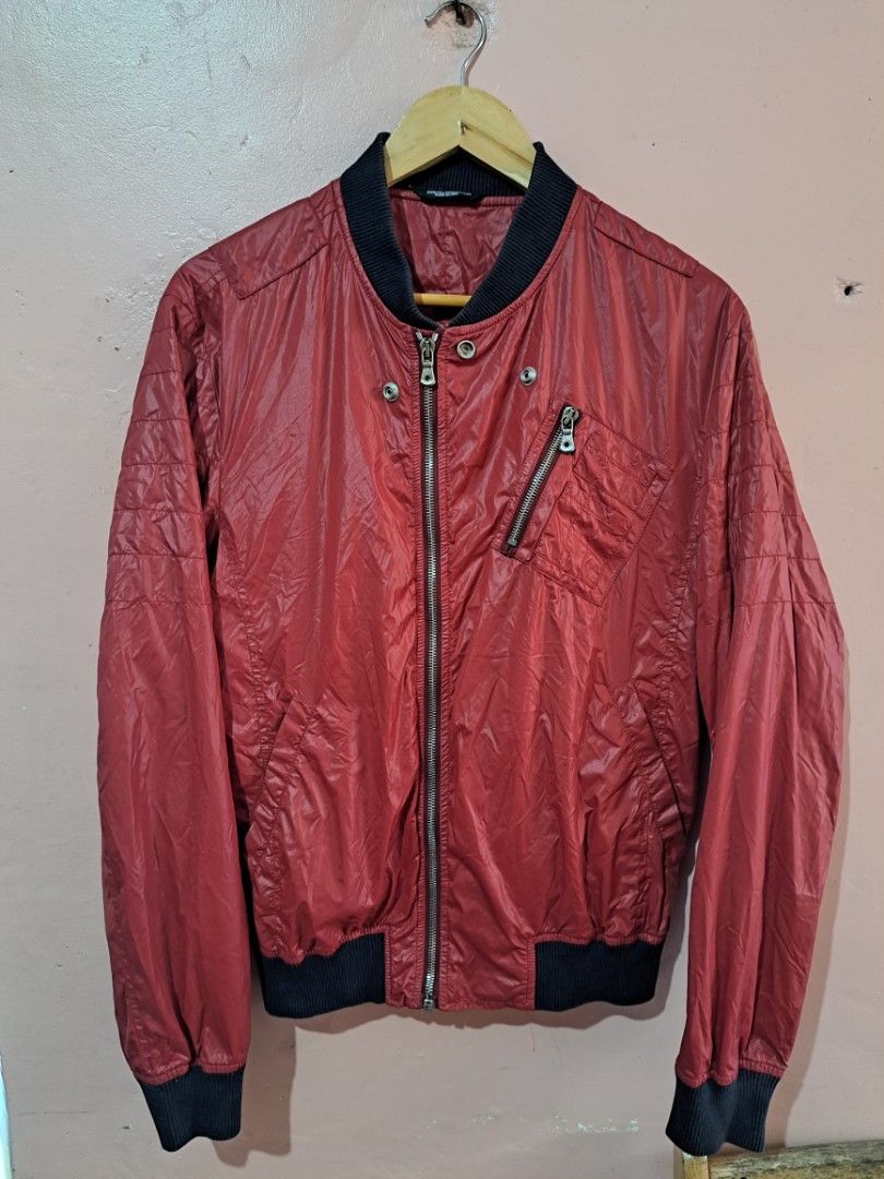 Dolce & Gabbana Red Bomber Jacket (Category: Luxury Apparel) located in Baguio. Submitted by randomthrifts2600 (Listing ID 1428910905, Image 2). Description: Dolce & Gabbana red nylon bomber jacket. This specific design features a rib-knit collar, cuffs, and hem in a contrasting black color. Key Features Design: A lightweight windbreaker or bomber-style jacket with a distinctive slanted zipper pocket on the left chest. Details: It includes snap-b