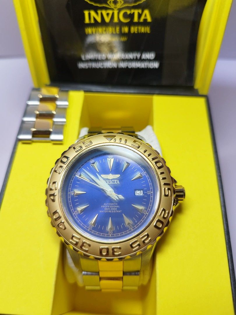 Invicta Automatic Watch with Blue Dial (Category: Men's Watches) located in Pangil. Submitted by kopee_matcha (Listing ID 1428936787, Image 2). Description: Invicta automatic watch with a blue dial and gold-tone bezel. It features a stainless steel band and comes with an extra link. The watch is presented in its original yellow box, along with warranty and instruction information. The back of the watch shows the automatic movement. Bought abroad 