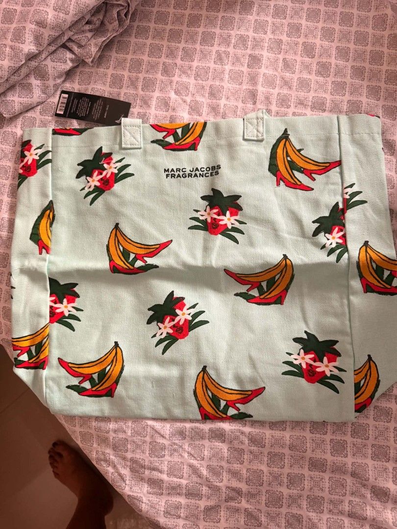 Marc Jacobs Fragrances Tote Bag (Category: Luxury Bags & Wallets) located in Mandaluyong City. Submitted by summerinjun (Listing ID 1428801411, Image 2). Description: Marc Jacobs tote bag features a unique print with strawberries, bananas, and high heels. It has a light blue background and a handle. The tag indicates it's from Marc Jacobs Fragrances. Perfect for carrying your essentials in style..