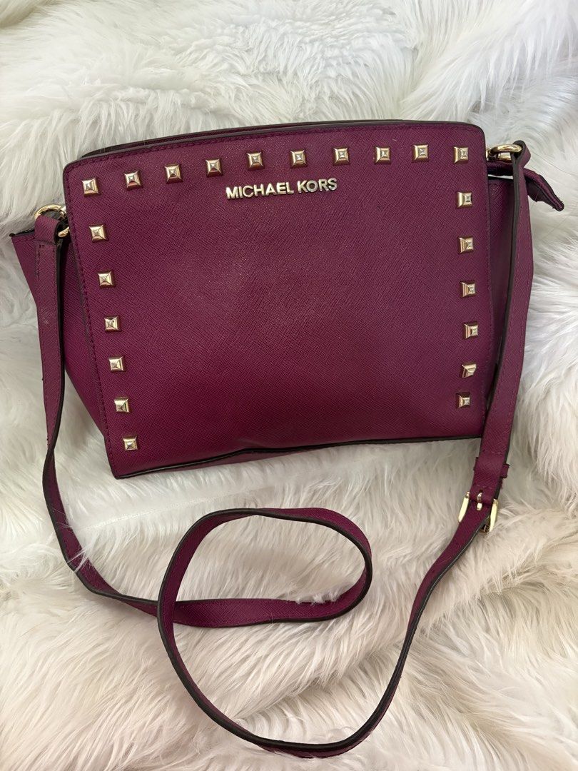 Michael Kors Studded Crossbody Bag (Category: Luxury Bags & Wallets) located in Davao. Submitted by emmanuelchuamellorin23 (Listing ID 1428810963, Image 2). Description: Michael Kors crossbody bag features a deep purple color with gold-tone studs. It has a zip closure and a long strap for shoulder or crossbody wear. The interior has a fabric lining with the Michael Kors logo. The bag has a gold-tone zipper with the Michael Kors logo..