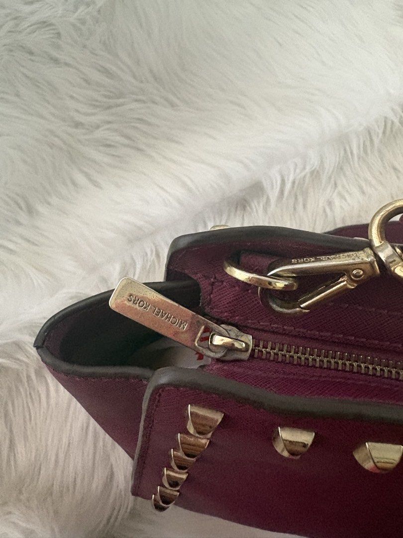 Michael Kors Studded Crossbody Bag (Category: Luxury Bags & Wallets) located in Davao. Submitted by emmanuelchuamellorin23 (Listing ID 1428810963, Image 3). Description: Michael Kors crossbody bag features a deep purple color with gold-tone studs. It has a zip closure and a long strap for shoulder or crossbody wear. The interior has a fabric lining with the Michael Kors logo. The bag has a gold-tone zipper with the Michael Kors logo..