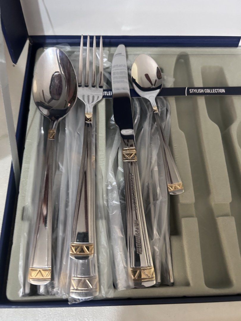 Stylish Collection Cutlery Set (Category: Dinnerware & Cutlery) located in Lubao. Submitted by appleglaze (Listing ID 1428814101, Image 1). Description: Elegant cutlery set from the Stylish Collection. The set includes a spoon, fork, knife, and another spoon. The handles have a silver and gold design. The set is in its original packaging..