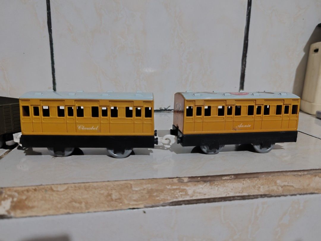 Thomas the Tank Engine Train Set 1992 - 2002 (Category: Vehicle & Diecast Models) located in Pasig City. Submitted by geraldnee28280 (Listing ID 1428967160, Image 3). Description: Thomas the Tank Engine train set. It includes the Thomas engine, two cargo cars, and two passenger cars named Annie and Clarabel. The engine is blue with red accents. The passenger cars are yellow. The train set is made by Tomy and is marked as made in Thailand..