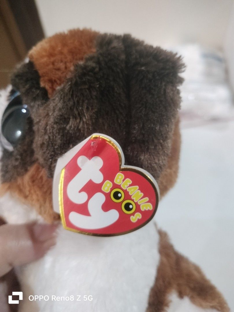 Ty Beanie Boos Duke Stuffed Dog (Category: Plushies & Soft Toys) located in Tanza. Submitted by ireennee (Listing ID 1428821716, Image 3). Description: Adorable Ty Beanie Boos Duke stuffed dog features big, sparkly blue eyes and a soft, plush body. It has brown and white fur with brown ears and a cute little tail. The original Ty tag is still attached. A perfect cuddly companion for kids and collectors alike..