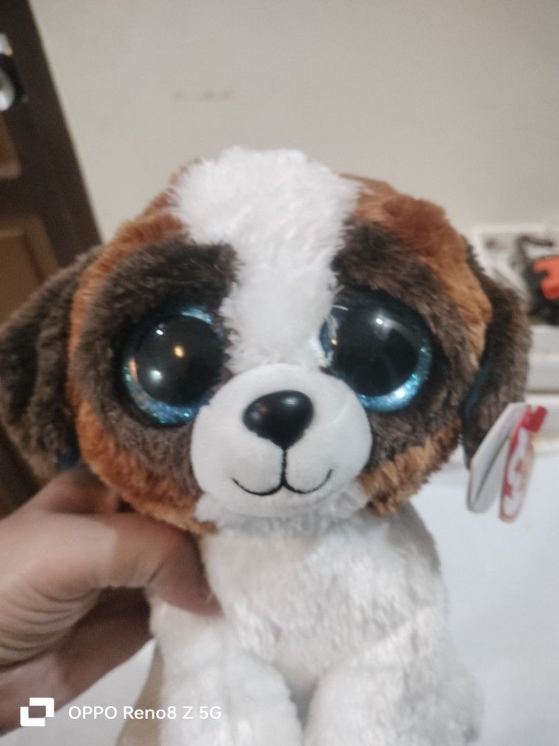 Ty Beanie Boos Duke Stuffed Dog (Category: Plushies & Soft Toys) located in Tanza. Submitted by ireennee (Listing ID 1428821716, Image 2). Description: Adorable Ty Beanie Boos Duke stuffed dog features big, sparkly blue eyes and a soft, plush body. It has brown and white fur with brown ears and a cute little tail. The original Ty tag is still attached. A perfect cuddly companion for kids and collectors alike..