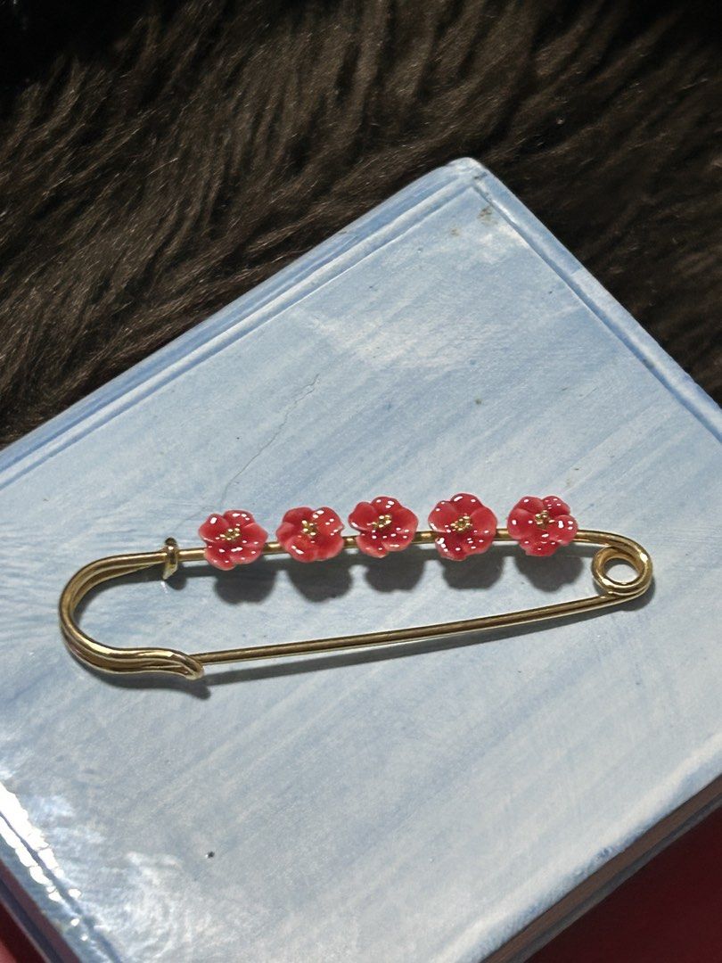 Bo24Floral Brooch Pin (Category: Brooches) located in Angeles City. Submitted by zyeplustradings (Listing ID 1428996430, Image 2). Description: Brooch pin features a gold-toned safety pin design adorned with five red flower accents. Each flower has a small, gold-colored center. The pin is designed to be a decorative accessory. It can be used to add a touch of elegance to clothing or accessories..