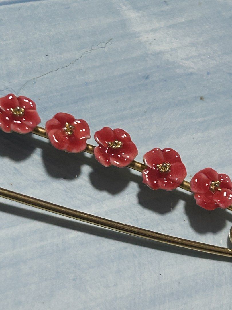 Bo24Floral Brooch Pin (Category: Brooches) located in Angeles City. Submitted by zyeplustradings (Listing ID 1428996430, Image 3). Description: Brooch pin features a gold-toned safety pin design adorned with five red flower accents. Each flower has a small, gold-colored center. The pin is designed to be a decorative accessory. It can be used to add a touch of elegance to clothing or accessories..
