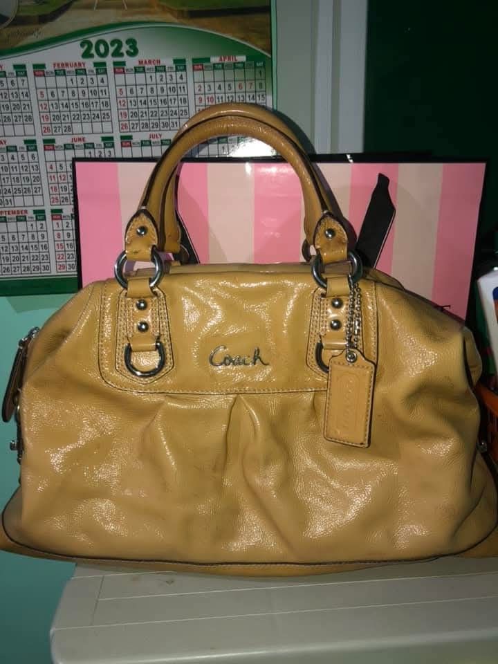 Coach Leather Handbag (Category: Luxury Bags & Wallets) located in Pugo. Submitted by abshopfinity (Listing ID 1429158653, Image 1). Description: Tan Coach handbag with a light purple interior. Features a zip closure and double handles. Includes a Coach hang tag. The interior has multiple compartments. The bag has silver hardware and a Coach logo on the front. The serial number is B1248-F16464..