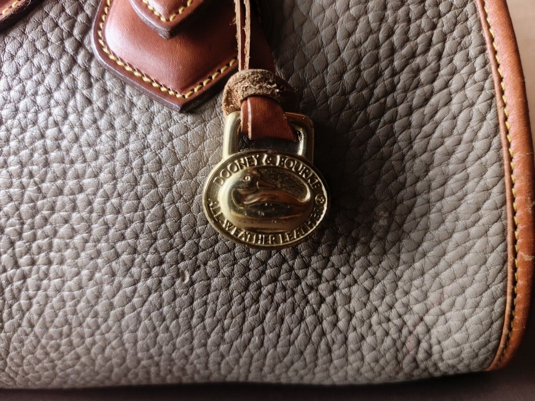 Dooney & Bourke All Weather Doctors Bag (Category: Luxury Bags & Wallets) located in Quezon City. Submitted by thriftymnl_ (Listing ID 1429122056, Image 3). Description: Brand: Dooney & Bourke Style: Satchel / Doctor’s Bag Material: Pebbled All Weather Leather, Smooth Leather Trim, Solid Brass Hardware Color: Taupe (Body) & British Tan (Trim) Features: Iconic leather duck seal on the front, hanging brass duck fob, structured top handles, and full