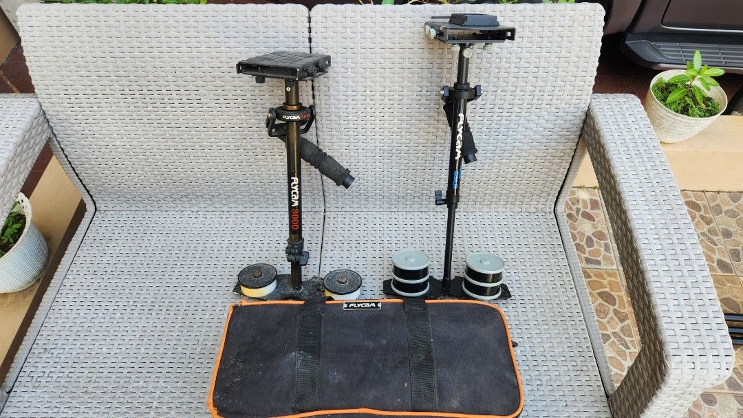 Flycam 3000 & Nano DSLR Stabilizer (Category: Cameras) located in Antipolo. Submitted by luislasi (Listing ID 1429092590, Image 2). Description: Listing includes a Flycam 3000 and a Nano DSLR stabilizer, both with one carrying bag. The Flycam 3000 has a black handle and a red "3000" marking. The Nano DSLR stabilizer is black with white "Flycam" and "nano DSLR" markings. Both stabilizers include counterweights. This lot is buy buy 1 take 1. As is 