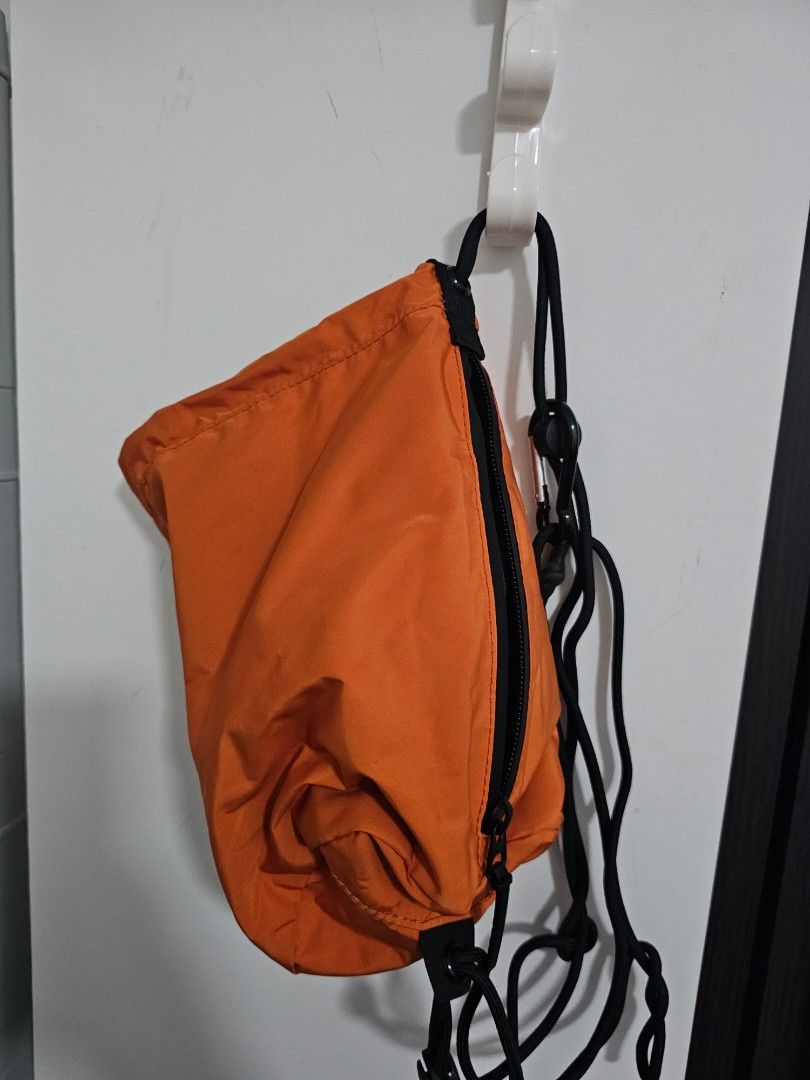 Uniqlo Beach Orange Sling Bag (Category: Cross-body Bags) located in Las Pinas. Submitted by specteretceps (Listing ID 1429064007, Image 1). Description: Sling bag features a vibrant orange exterior with a black zipper and strap. The interior is black. It has a drawstring closure and a compact design, perfect for carrying essentials. It's a simple, functional bag for everyday use..