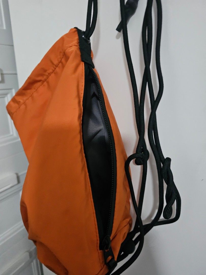 Uniqlo Beach Orange Sling Bag (Category: Cross-body Bags) located in Las Pinas. Submitted by specteretceps (Listing ID 1429064007, Image 3). Description: Sling bag features a vibrant orange exterior with a black zipper and strap. The interior is black. It has a drawstring closure and a compact design, perfect for carrying essentials. It's a simple, functional bag for everyday use..