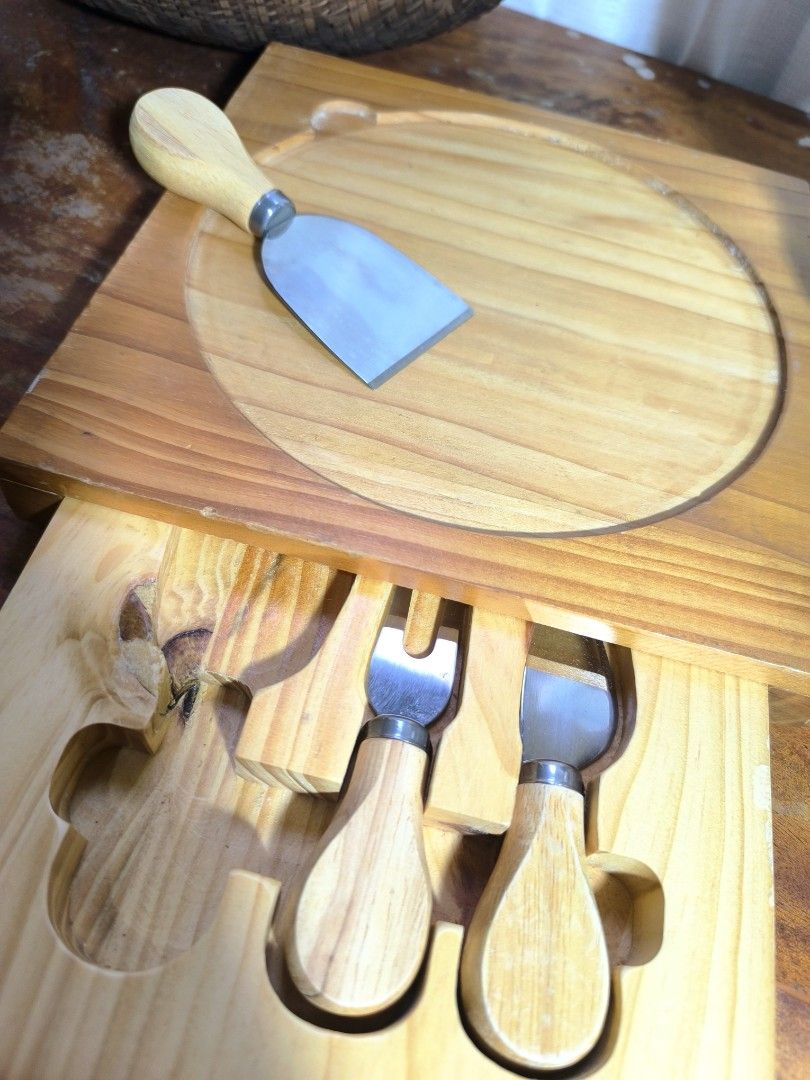 Wooden Cheese Board Set with Knives (Category: Knives & Chopping Boards) located in Pangil. Submitted by kopee_matcha (Listing ID 1429075881, Image 3). Description: Cheese board set includes a wooden board with a circular inset and a drawer containing three cheese knives. The knives have wooden handles and stainless steel blades. The board is square-shaped with a natural wood finish..