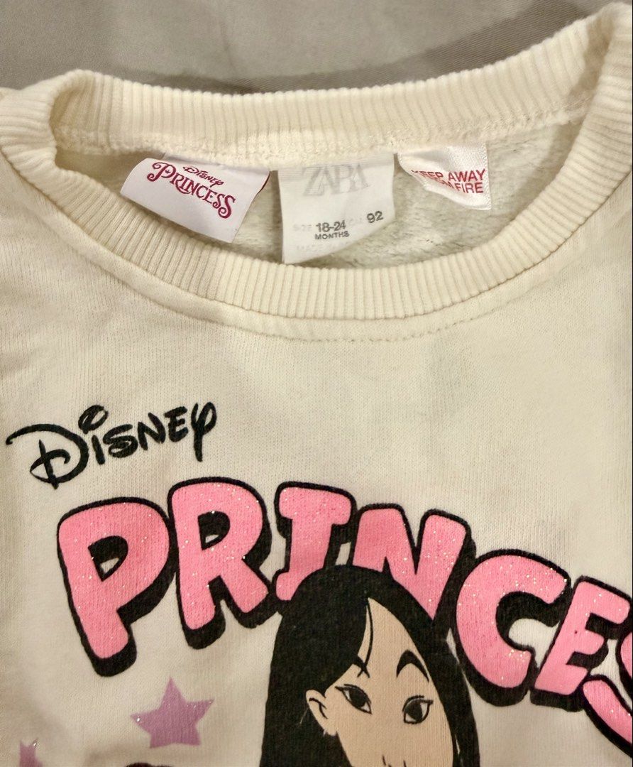 Zara Disney Princess Sweatshirt (Category: Babies & Kids Fashion) located in Paranaque City. Submitted by mrschuadeclutter (Listing ID 1429053636, Image 2). Description: Adorable Zara sweatshirt featuring Disney princesses. It has a crew neck and long sleeves. The size is 18-24 months, and the color is off-white. The graphic features Belle, Snow White, Mulan, and Rapunzel. Perfect for your little princess!.