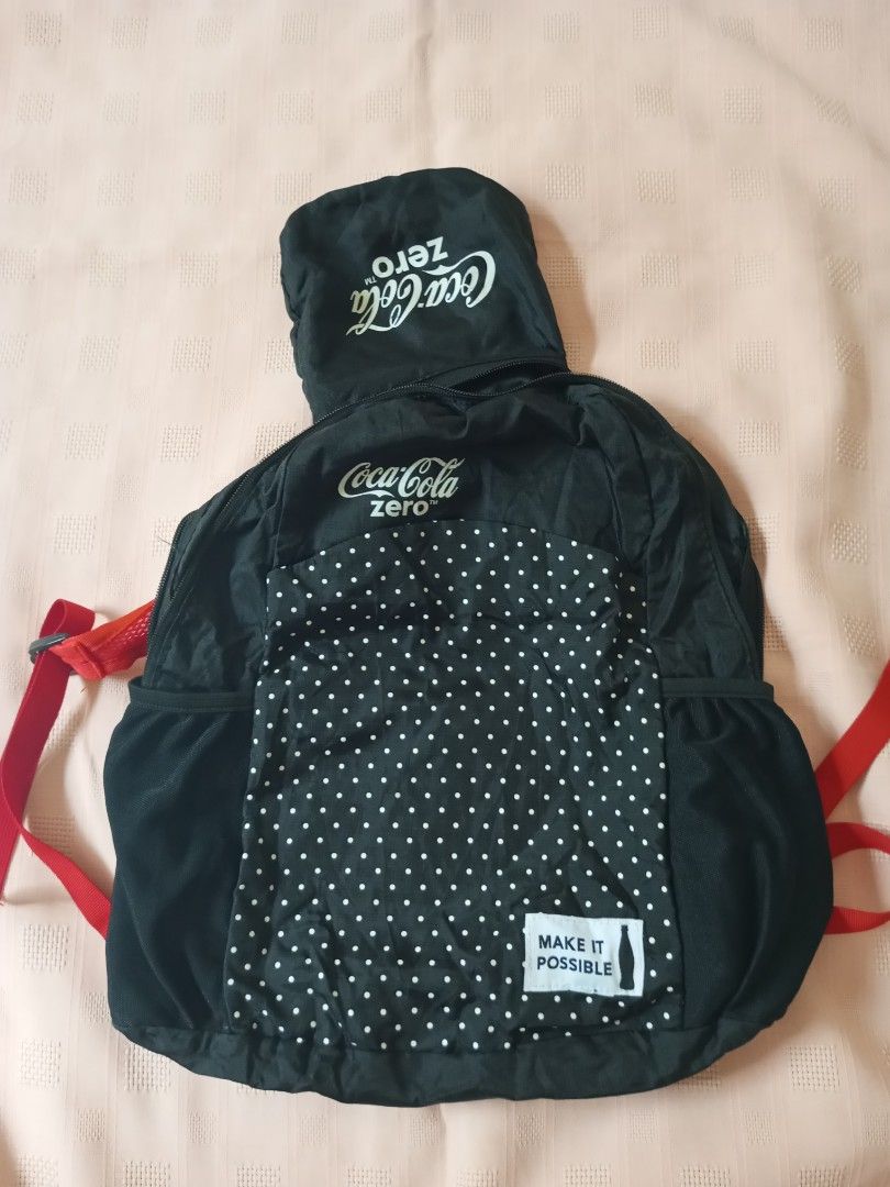 Coca-Cola Zero Foldable Backpack (Category: Backpacks) located in Quezon City. Submitted by jojoleen28 (Listing ID 1424350615, Image 2). Description: Made of light, polyester/nylon combination. Coca-Cola Zero backpack is foldable and features a black exterior with the Coca-Cola Zero logo. It has red straps and a polka-dot pattern on the back. The backpack includes a small pocket and a "Make It Possible" tag. It can be folded into a compact size f