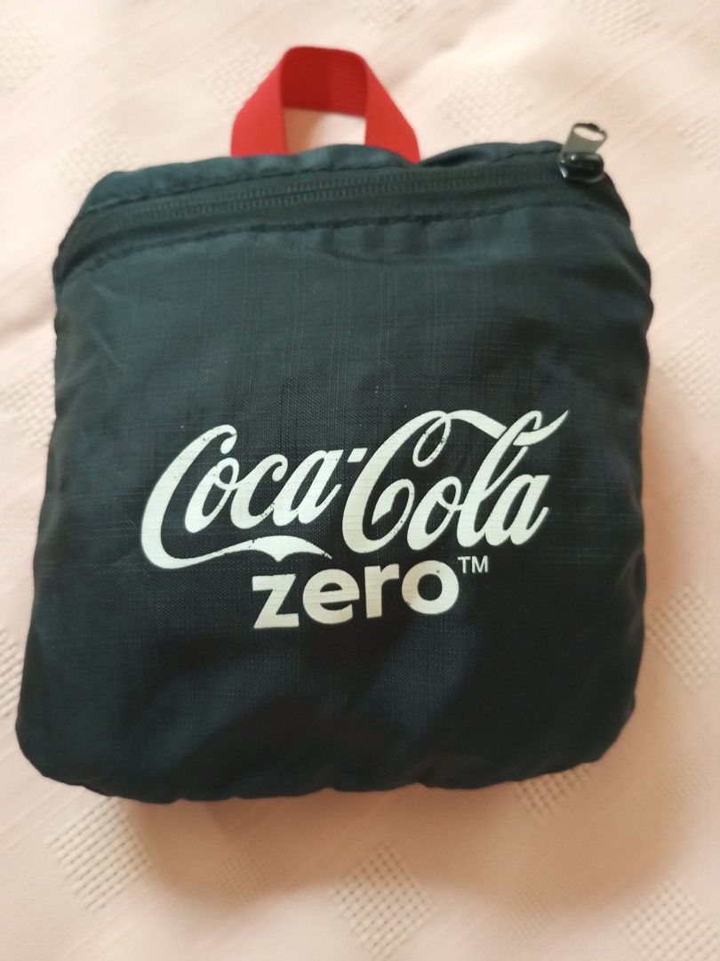 Coca-Cola Zero Foldable Backpack (Category: Backpacks) located in Quezon City. Submitted by jojoleen28 (Listing ID 1424350615, Image 1). Description: Made of light, polyester/nylon combination. Coca-Cola Zero backpack is foldable and features a black exterior with the Coca-Cola Zero logo. It has red straps and a polka-dot pattern on the back. The backpack includes a small pocket and a "Make It Possible" tag. It can be folded into a compact size f