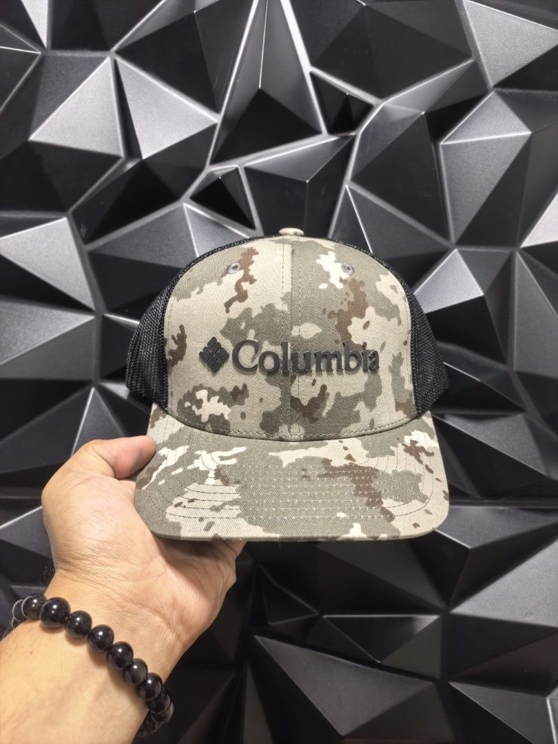 Columbia Camo Trucker Cap (Category: Caps & Hats) located in Bacoor. Submitted by secretsup (Listing ID 1424456334, Image 1). Description: Columbia cap with a camouflage pattern on the front panel and a black mesh back. Features the Columbia logo on the front. The cap has an adjustable strap for a comfortable fit. The size is OS (One Size)..