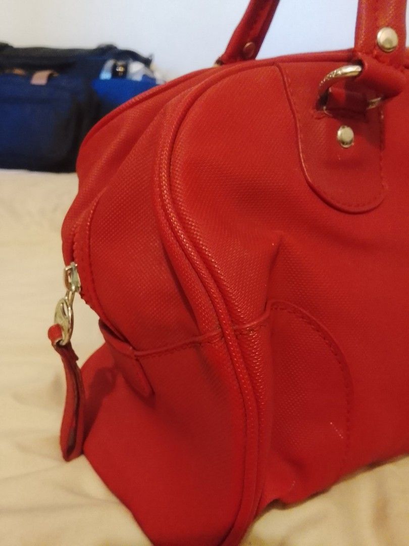 Lacoste Red Handbag (Category: Luxury Bags & Wallets) located in Manila. Submitted by dcsago (Listing ID 1424351977, Image 2). Description: - Red Lacoste handbag - Zip closure - Green interior - Lacoste logo on front and zipper pull - Two handles - Small side pocket - Textured material.