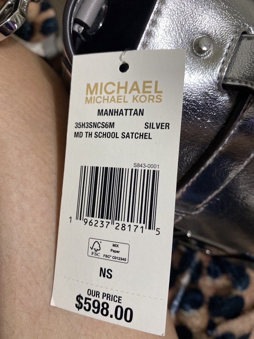 Michael Kors Manhattan MD TH School Satchel (Category: Luxury Bags & Wallets) located in Pagadian. Submitted by maximaxcollection (Listing ID 1424454567, Image 2). Description: Silver Michael Kors Manhattan MD TH School Satchel. Features a top handle and a detachable shoulder strap with the Michael Kors logo. The bag has a flap closure with a metal clasp. The original price tag is still attached, showing a price of $598.00. The bag has a silver f