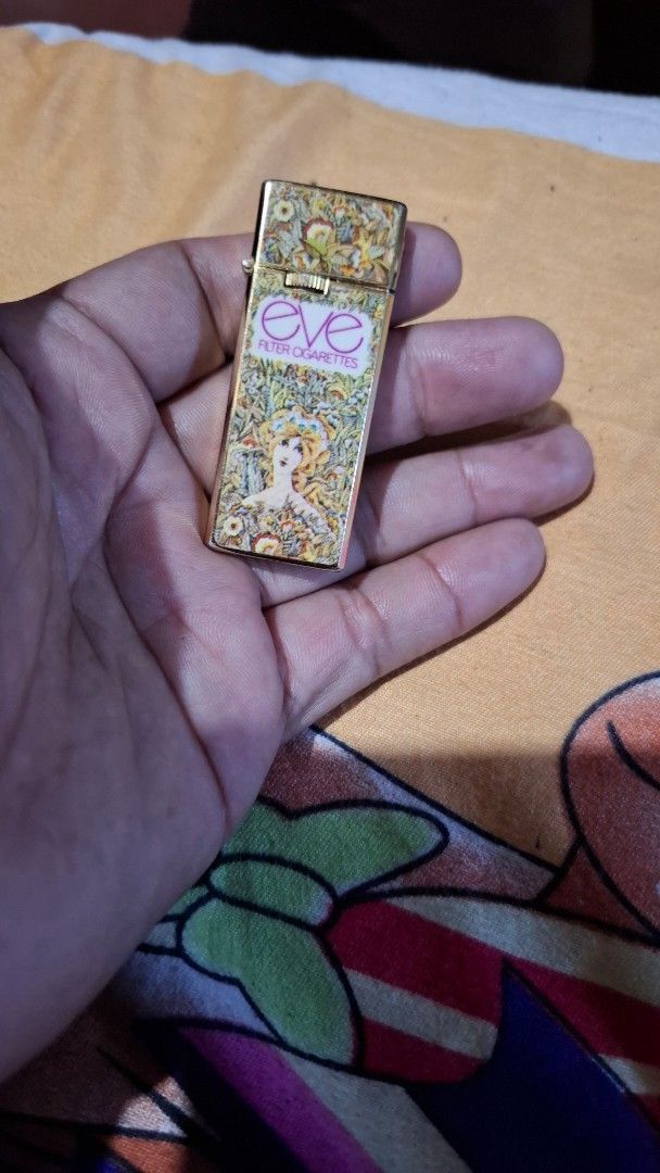 Penguin Sharp Eve Cigarette Lighter (Category: Vintage Collectibles) located in Antipolo. Submitted by goldentiger-ac44 (Listing ID 1424515764, Image 2). Description: - Vintage Penguin Sharp lighter - Features an Eve cigarette design - Gold-colored body - Rectangular shape with flip-top design - Decorative Eve logo and artwork - Brand: Penguin Sharp.