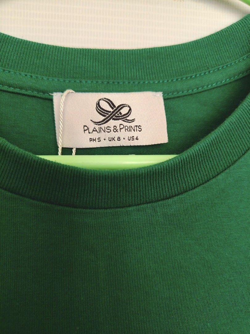 Plains & Prints Green Graphic Tee (Category: Shirts) located in Batangas. Submitted by 2mspreloved (Listing ID 1424346115, Image 2). Description: - Plains & Prints t-shirt - Green color - Features a graphic print of women in dresses - Size: PHS S, UK 6, US 4 - Short sleeves - Round neckline.