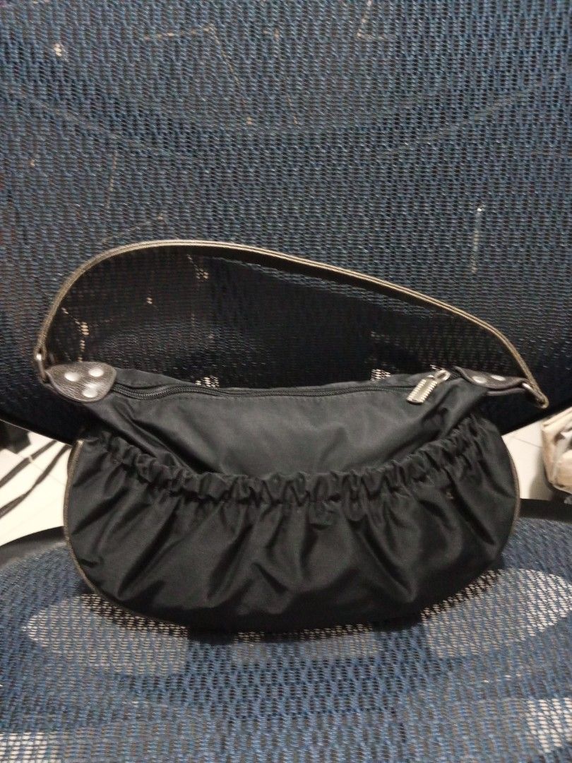Black Nylon Kili kili Bag (Category: Shoulder Bags) located in Davao. Submitted by zoiesells_63 (Listing ID 1429306264, Image 2). Description: Black shoulder bag with a unique design. Features a gathered fabric detail on the front with decorative metal accents. The bag has a single shoulder strap and a zipper closure. The bag's shape is rounded, and it has a zipper on the side..
