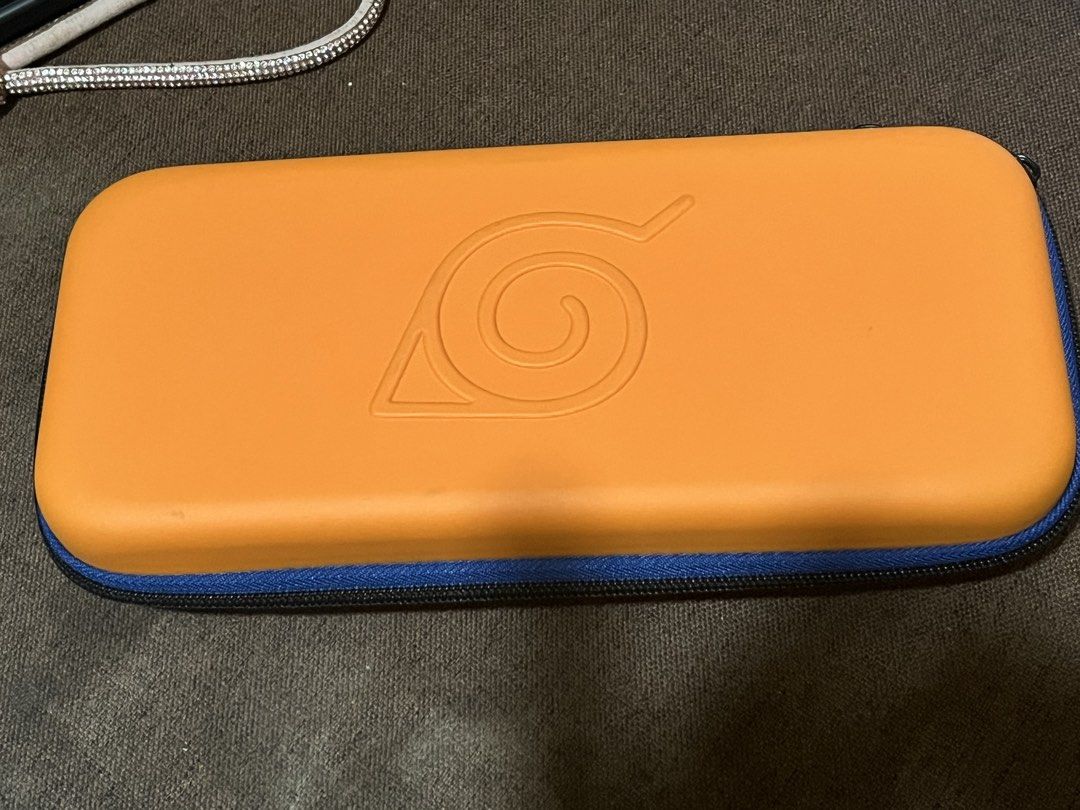 Naruto Nintendo Switch Carrying Case (Category: Cases & Covers) located in Taguig. Submitted by random.stuff31 (Listing ID 1429217503, Image 1). Description: Selling this Naruto-themed carrying case for Nintendo Switch. Features the iconic Hidden Leaf Village symbol and “©2002 Masashi Kishimoto” print—perfect for anime fans! Sturdy outer shell helps protect your Switch from scratches, bumps, and dust. Compact and travel-friendly with zipper closu