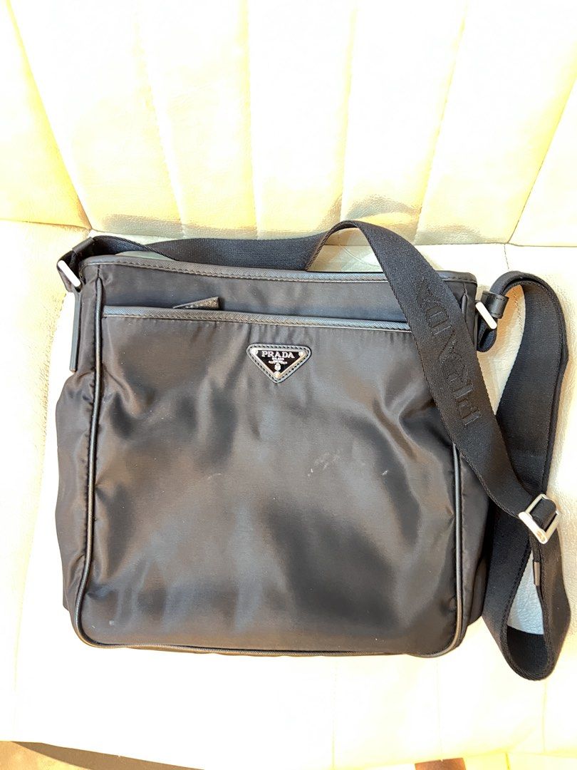Prada Messenger Bag (Category: Luxury Bags & Wallets) located in Mandaluyong City. Submitted by ilovenicethings888 (Listing ID 1429287036, Image 1). Description: Black Prada messenger bag. Features a front flap with the Prada logo and a shoulder strap with the Prada logo. The bag has multiple compartments, including a main compartment and a front pocket. The interior has a Prada logo tag..