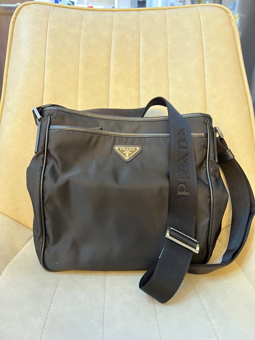 Prada Messenger Bag (Category: Luxury Bags & Wallets) located in Mandaluyong City. Submitted by ilovenicethings888 (Listing ID 1429287036, Image 2). Description: Black Prada messenger bag. Features a front flap with the Prada logo and a shoulder strap with the Prada logo. The bag has multiple compartments, including a main compartment and a front pocket. The interior has a Prada logo tag..