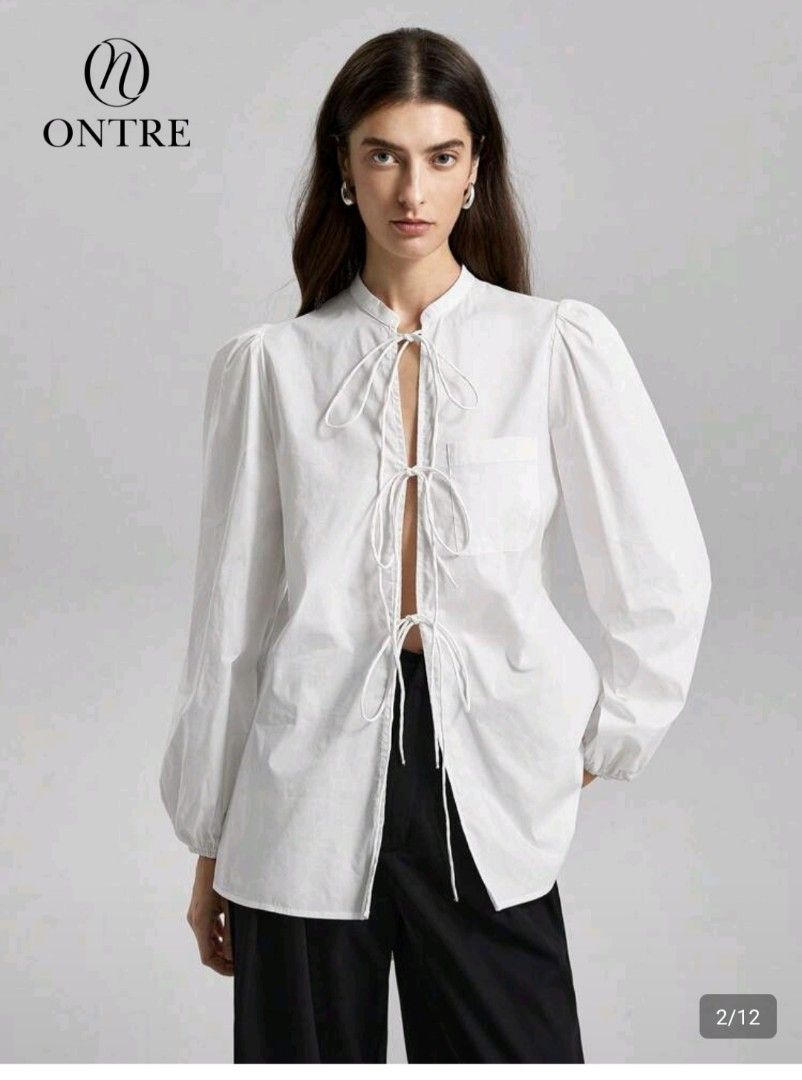 SHEIN Blouse with Tie Front (Category: Blouses) located in Las Pinas. Submitted by mgr29 (Listing ID 1429176706, Image 2). Description: LOOSE CAN FIT SMALL - SEMI LARGE White blouse from SHEIN with a tie-front design. Features long sleeves with puff shoulders. The blouse has a mandarin collar and a relaxed fit. The tag is still attached. Perfect for a casual yet stylish look..