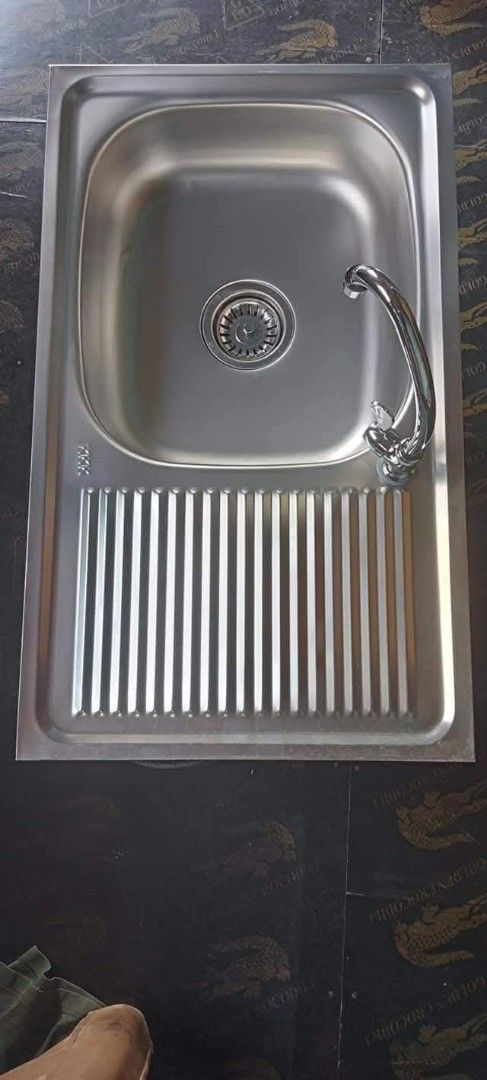 Stainless Steel Kitchen Sink with Drainboard (Category: Bathroom & Kitchen Fixtures) located in Manila. Submitted by muranglababo_ph2026 (Listing ID 1429179832, Image 3). Description: Stainless steel kitchen sink with a drainboard. Includes faucet and other accessories. Features a single basin design. The drainboard has a ribbed design. The sink is rectangular in shape..