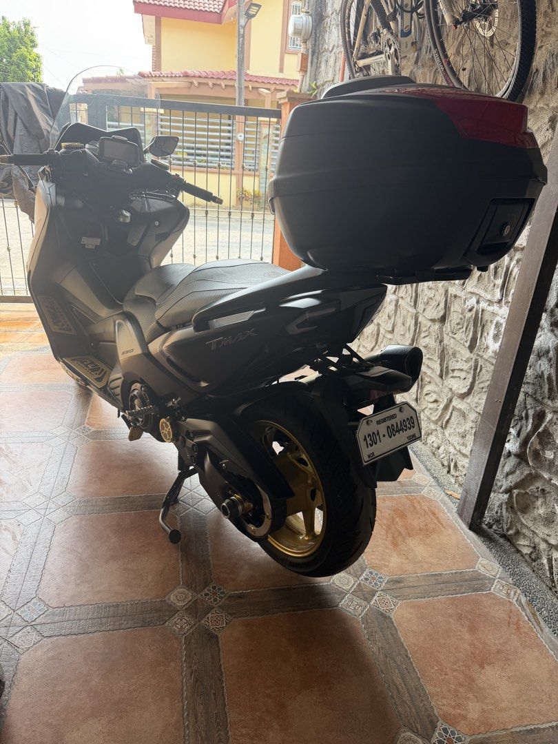 Yamaha TMAX 530 (Category: Motorbikes for Sale) located in Manila. Submitted by sandy03tol59753 (Listing ID 1429299151, Image 3). Description: Yamaha TMAX 560 motorcycle. Features a black top box, gold rims, and a custom exhaust. The motorcycle has a grey body with a tinted windscreen. The license plate number is 1301-0844939. Includes a passenger seat and a sleek design..
