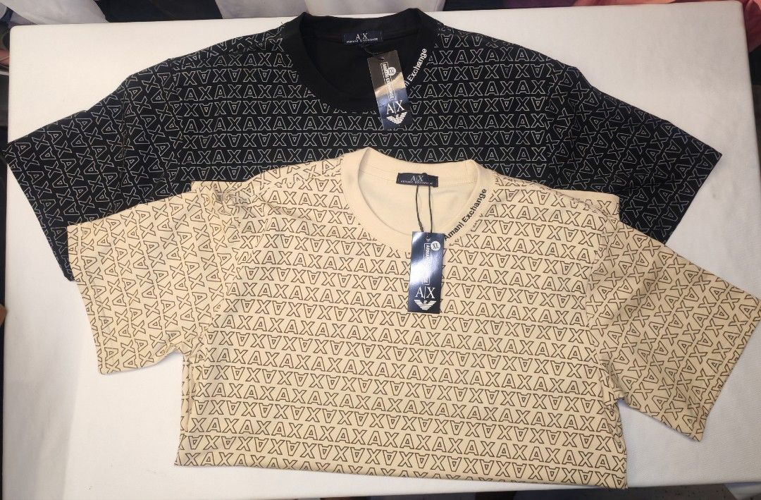 Armani Exchange AX T-Shirt (Category: Tshirts & Polo Shirts ) located in Quezon City. Submitted by rowem (Listing ID 1429479365, Image 2). Description: Armani Exchange AX T-shirts available in black beige, white and gray. Features an all-over AX logo pattern. Comes with original tags. The beige shirt has "Armani Exchange" printed on the neckline. Short-sleeved and likely made of a comfortable fabric. Sizes Available XL/XXL/XXXL.
