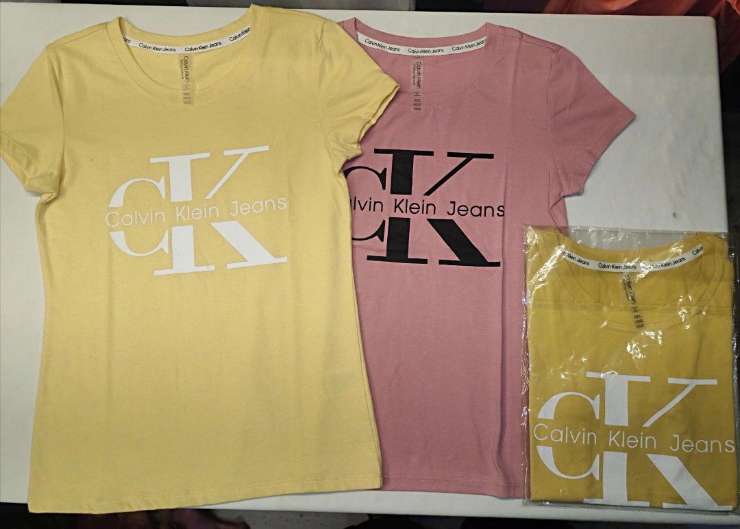 Calvin Klein Jeans T-shirts (Category: Shirts) located in Quezon City. Submitted by rowem (Listing ID 1429476473, Image 1). Description: These Calvin Klein Jeans t-shirts are available in yellow and pink. They feature the Calvin Klein Jeans logo on the front. The t-shirts appear to be unworn and are still in their original packaging. They have a classic crew neck design..