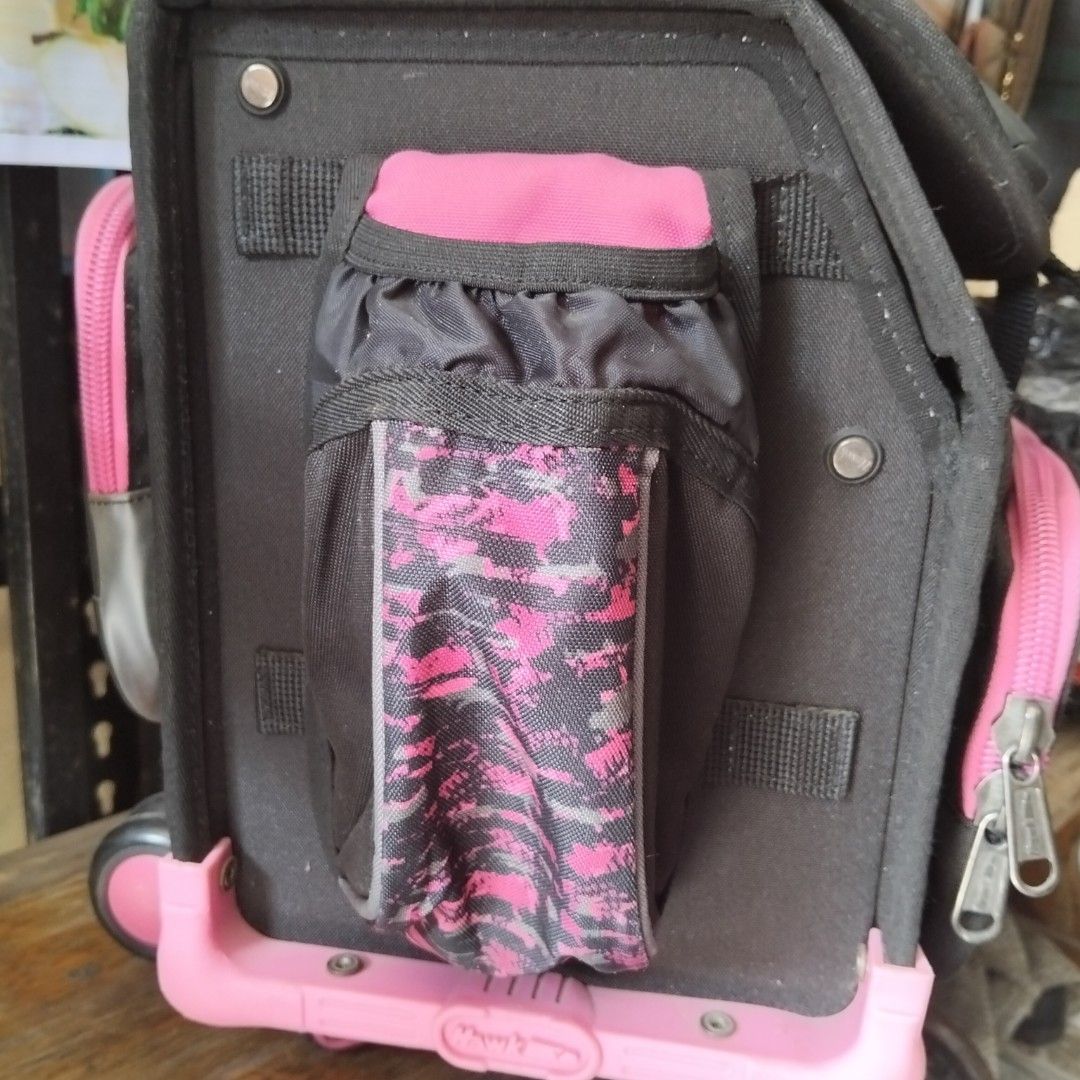 Hawk Rolling Backpack with Lunch Bag (Category: Strollers) located in Quezon City. Submitted by heybailey (Listing ID 1429386142, Image 3). Description: Hawk rolling backpack comes with a matching lunch bag. It features a pink and black color scheme with a camouflage pattern on some parts. The backpack has multiple compartments, including a side pocket for a water bottle. It has a handle and wheels for easy transport. The backpack also includes a