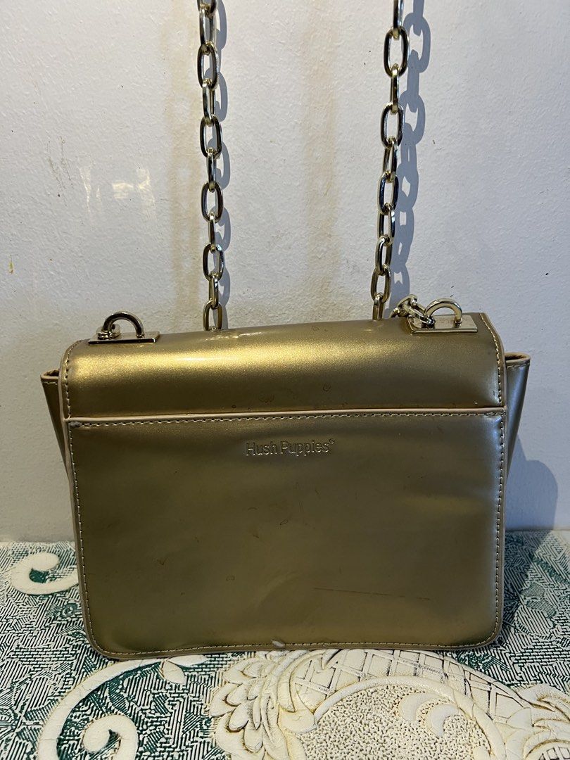 Hush Puppies Gold Chain Bag (Category: Luxury Bags & Wallets) located in Makati City. Submitted by nicolaylay (Listing ID 1429504022, Image 2). Description: Gold-colored handbag from Hush Puppies. Features a chain strap and a rectangular shape with a flap closure. The bag has a gold-tone metal clasp and the Hush Puppies logo is visible on the back..