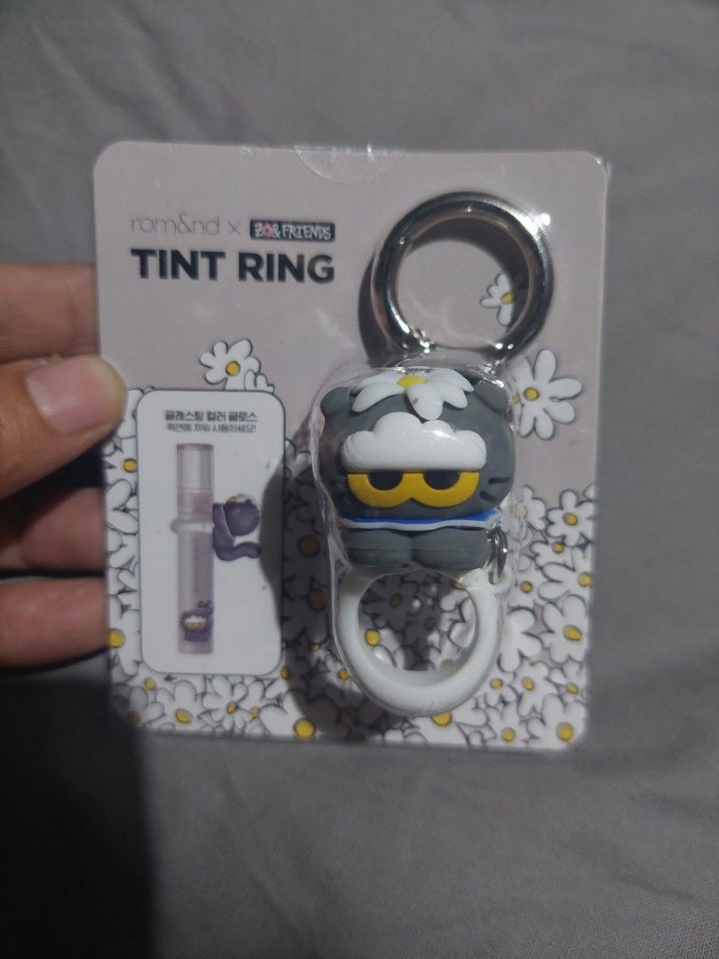 Limited Edition Rom&nd x Tint Ring Keyring (Category: Luxury Accessories) located in Quezon City. Submitted by miyascloset (Listing ID 1429456321, Image 1). Description: Rom&nd x Tint Ring keyring. It features a gray and white design with a white flower. The keyring has a silver ring and a white ring. this is the official Collab with GD zoa and friends and Romand Korean cosmetics brand. it is a keyring for your romand liptints. special and limite