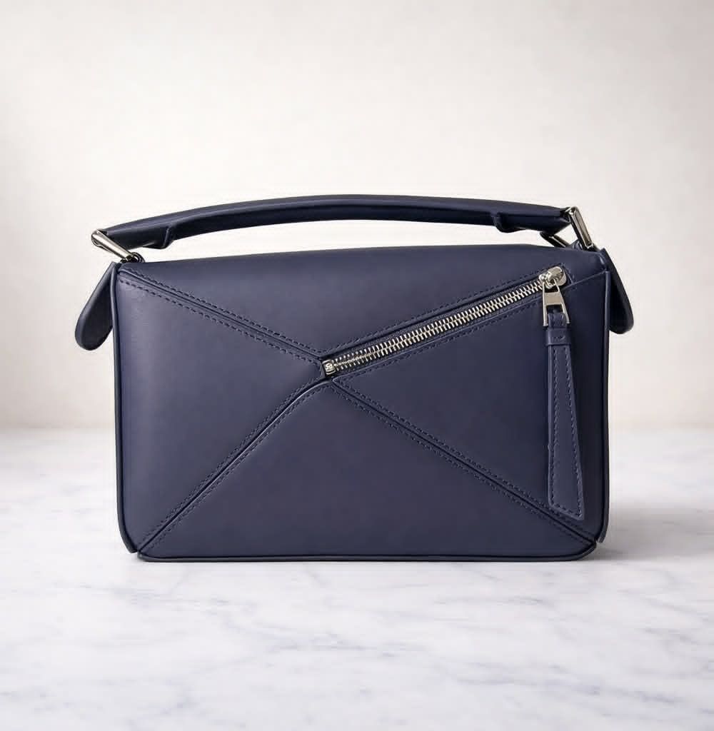 Loewe Puzzle Edge Small Bag Navy Blue (Category: Luxury Bags & Wallets) located in Cebu City. Submitted by theluxxaffair (Listing ID 1429484766, Image 2). Description: Authentic Loewe Puzzle Edge Small bag crafted in navy blue calfskin leather. It features a top handle and a detachable shoulder strap with the Loewe logo. The bag has a zipper closure, and the Loewe logo is embossed on the side. It includes a dust bag and a box. Length: 24 cm Heigh