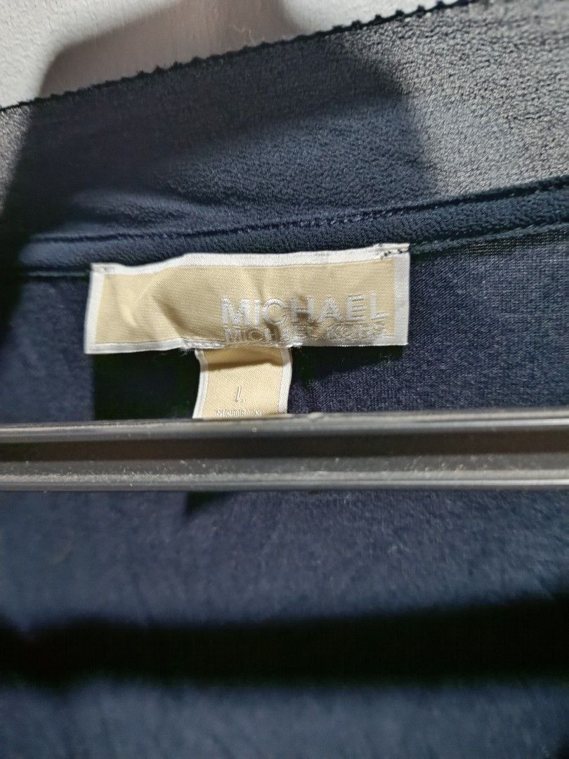 Michael Kors V-Neck T-Shirt (Category: Shirts) located in Subic. Submitted by yssacollection (Listing ID 1429495129, Image 3). Description: Dark blue Michael Kors V-neck t-shirt. Features a V-neck design with a contrasting trim. The tag indicates a size L. There is a small tear at the V-neck seam..