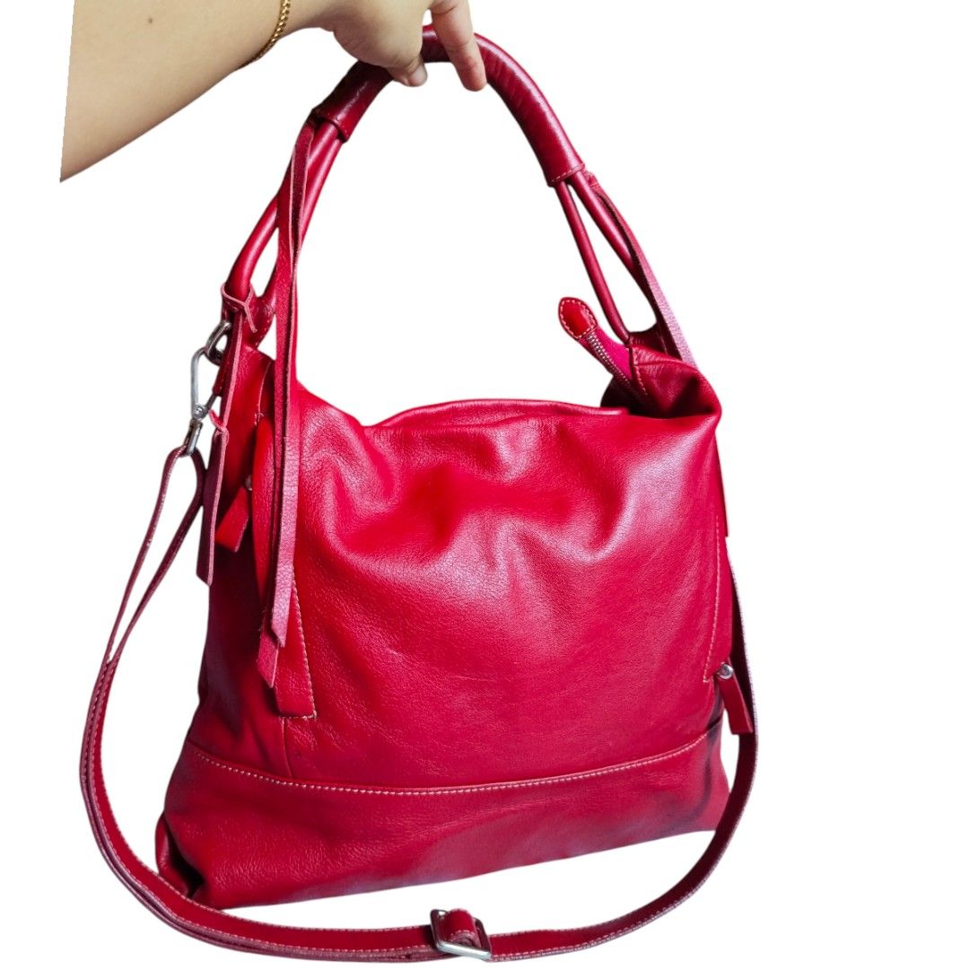 Michelangelo Leather Handbag - Made in Italy (Category: Luxury Bags & Wallets) located in Bacolod City. Submitted by maejuntado33 (Listing ID 1429400643, Image 2). Description: Genuine leather handbag by Michelangelo, made in Italy. Features a vibrant red exterior with a matching strap. The interior has a gray lining with multiple zippered compartments. Includes a detachable shoulder strap. The bag has a top handle and a zip closure. The brand ta