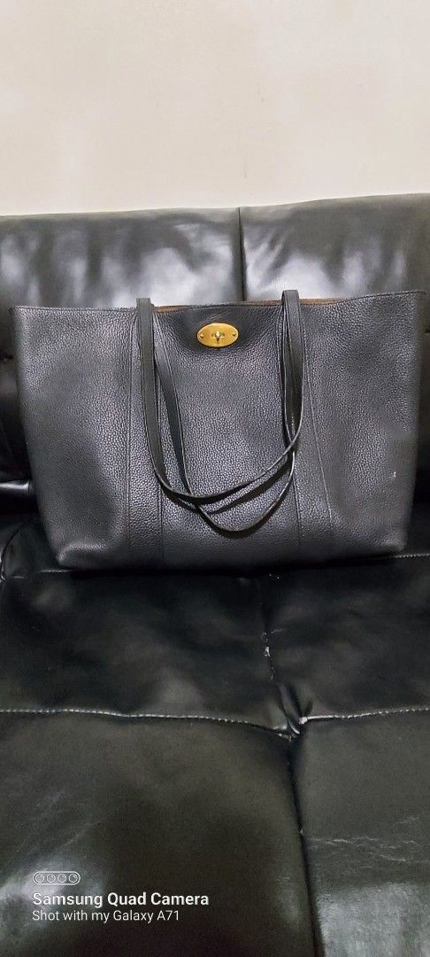 Mulberry Black Leather Tote Bag (Category: Luxury Bags & Wallets) located in Quezon City. Submitted by threetwotwo2ndaccount (Listing ID 1429503463, Image 1). Description: Black leather tote bag with a gold-tone clasp. Features a brown interior with a small pocket. The bag is marked "Made in England". The leather has a pebbled texture. The bag has two handles. There is a small tag with an "X" on it. size: H-13",L-17.5",W-5" issue: may minimal fla