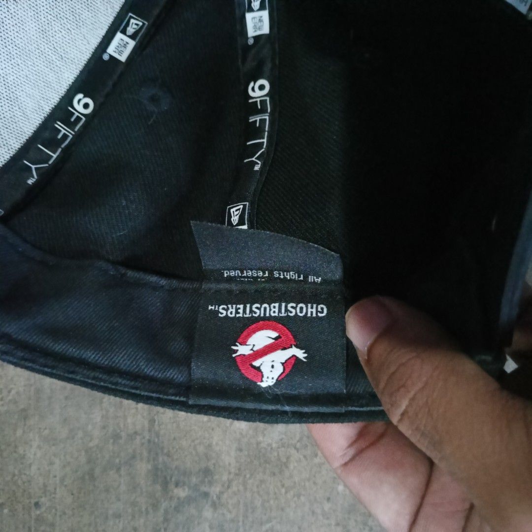 New Era Ghostbusters 9FIFTY Cap (Category: Caps & Hats) located in Penaranda. Submitted by flipmopickmo (Listing ID 1429376904, Image 3). Description: New Era 9FIFTY cap featuring the Ghostbusters logo. It has a black exterior with the Ghostbusters logo embroidered on the front. The cap is an original fit and made in Vietnam. The interior has the New Era and 9FIFTY tags. The cap has a snapback closure. Pre-owned Item.