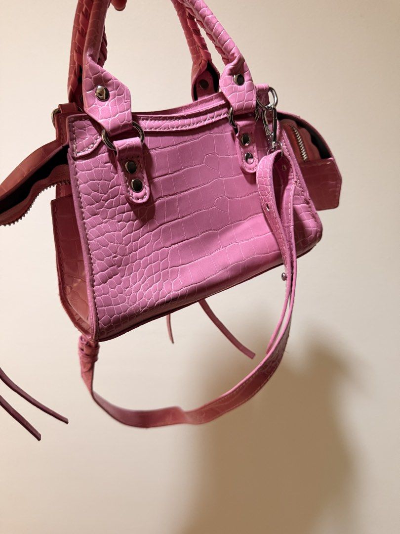 Pink Crocodile-Embossed Handbag (Category: Luxury Bags & Wallets) located in Taguig. Submitted by luxeria_ (Listing ID 1429361131, Image 2). Description: -Pink handbag - features a crocodile-embossed design. -It has a top handle and a detachable shoulder strap. -The bag has a zippered main compartment and a small pocket on the side. -The interior is black. -It has silver-tone hardware and decorative studs. -Balen Inspired only -negotiable.