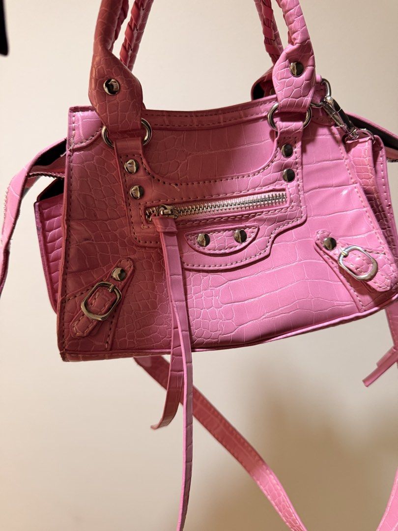 Pink Crocodile-Embossed Handbag (Category: Luxury Bags & Wallets) located in Taguig. Submitted by luxeria_ (Listing ID 1429361131, Image 1). Description: -Pink handbag - features a crocodile-embossed design. -It has a top handle and a detachable shoulder strap. -The bag has a zippered main compartment and a small pocket on the side. -The interior is black. -It has silver-tone hardware and decorative studs. -Balen Inspired only -negotiable.