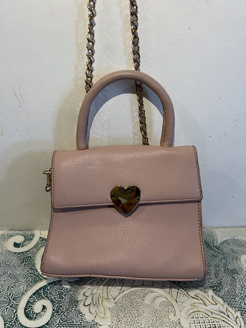 Pink Heart-Shaped Handbag with Chain Strap (Category: Shoulder Bags) located in Makati City. Submitted by nicolaylay (Listing ID 1429502548, Image 1). Description: Pink handbag features a heart-shaped clasp and a gold chain strap. It has a top handle and a flap closure. The interior is black. It's a stylish accessory for any outfit. PRICE IS NEGOTIABLE.