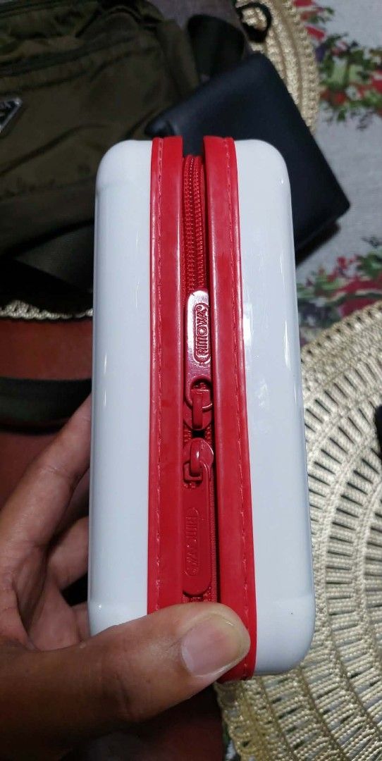 Porsche Rimowa (Category: Luxury Bags & Wallets) located in Puerto Princesa. Submitted by YeSurJOMS (Listing ID 1429364798, Image 3). Description: White Porsche Design pencil case with a red zipper and trim. Features the Porsche logo on the front. The interior is black. The case has a rectangular shape with a ridged design on the front and back. The zipper has the Porsche Design logo..