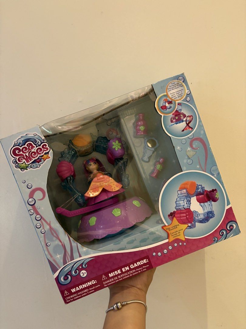 Sea Wees Mermaid Doll Playset (Category: Kids Toys) located in Quezon City. Submitted by lianas_preloved (Listing ID 1429340163, Image 2). Description: Sea Wees playset features a mermaid doll and various accessories. The box shows the doll in a purple and pink outfit with a seashell-themed base. It includes a water feature and other decorative elements. The packaging indicates it is suitable for ages 3+. The box also has some text in multiple la