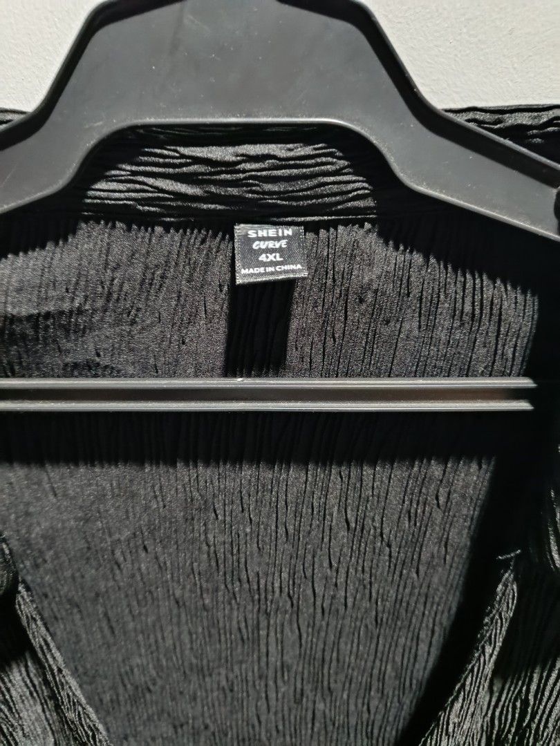 Shein Curve Pleated Blouse 4XL (Category: Blouses) located in Subic. Submitted by yssacollection (Listing ID 1429494729, Image 2). Description: Black pleated blouse from Shein Curve. It has a collared neckline and long sleeves. The blouse has a single button closure. The size is 4XL. The fabric has a textured, pleated design. The blouse is hanging on a black hanger..